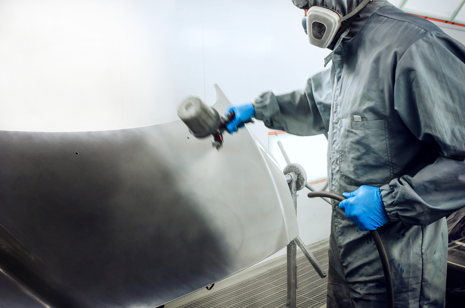 Car mechanic spraying paint on car hood